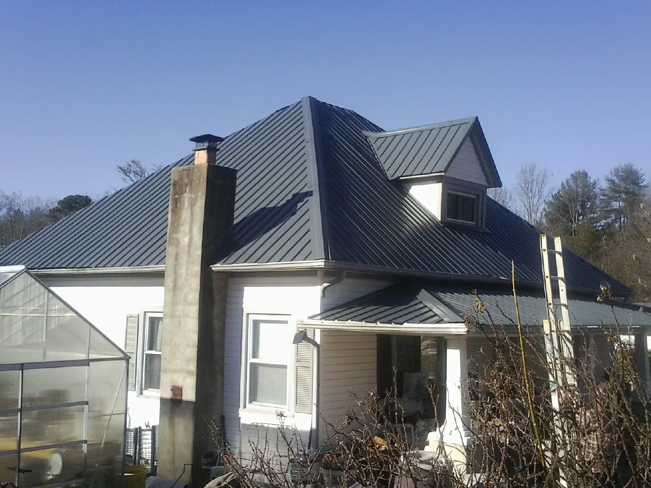 Dark blue standing seam metal roof on a white farmhouse with dormer — Slate & Tile Roof Repair by Roofing Brothers in Willernie