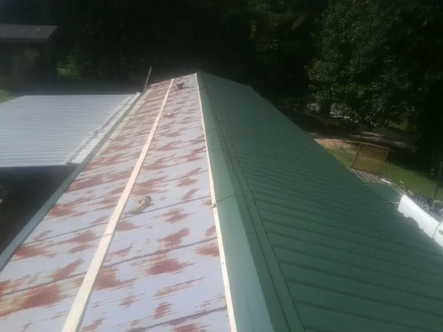 Old rusted panels beside newly installed green metal roofing — Wind Damage Roof Repair by Roofing Brothers in Willernie