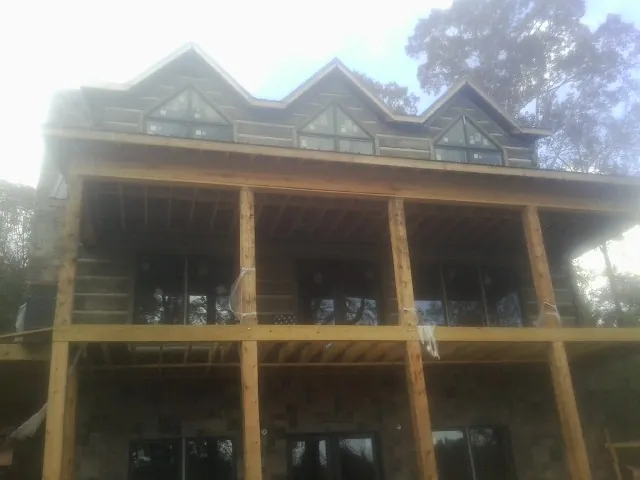 Dormers and porch framing on a large log home under construction — Roof Coating work by our crew in Willernie