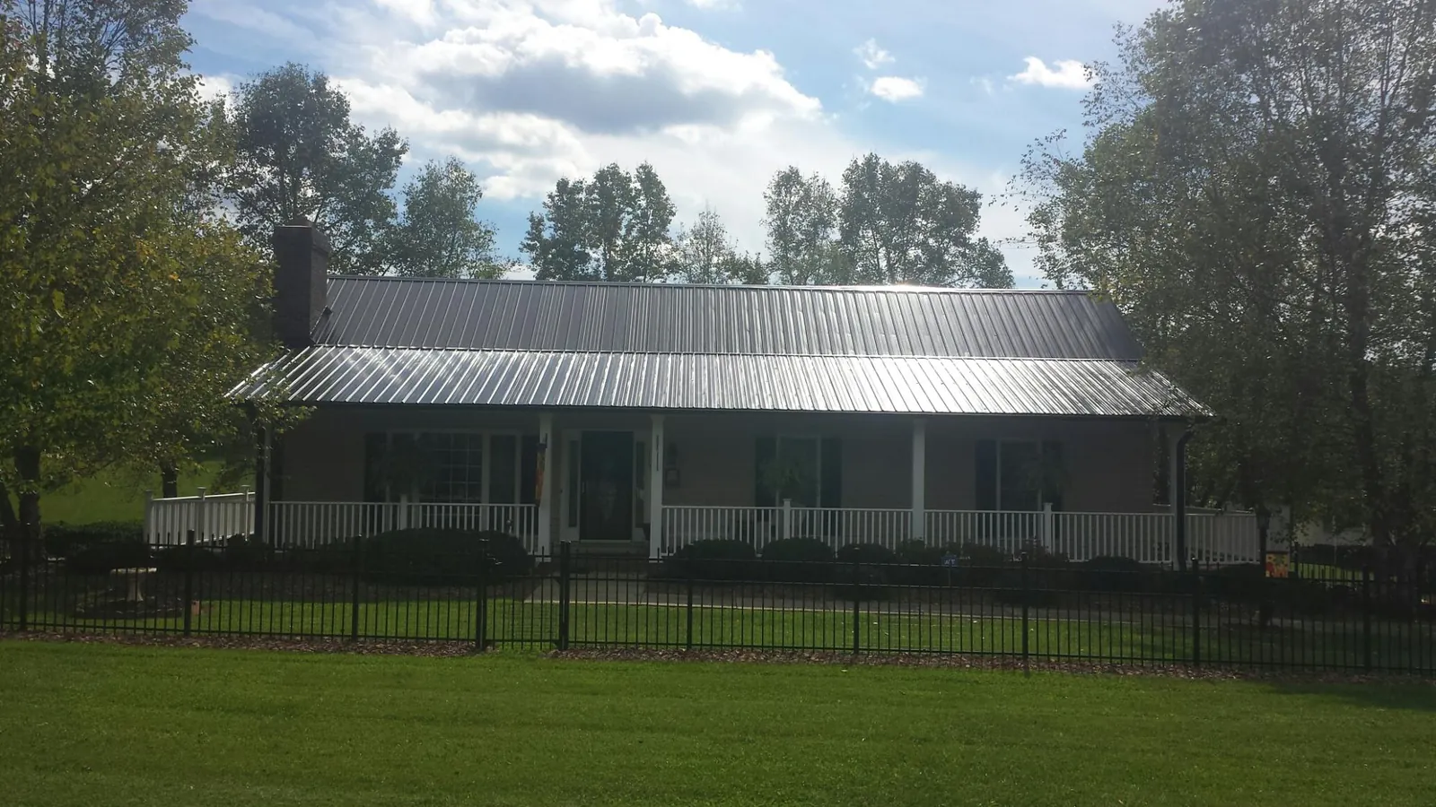 Gray metal roof on a brick ranch with a full width front porch — Gutter Guard Installation work by our crew in Willernie